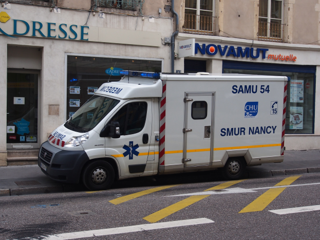 Ambulanz am Straßenrand vor einem Gebäude mit Krankenhausschild geparkt.