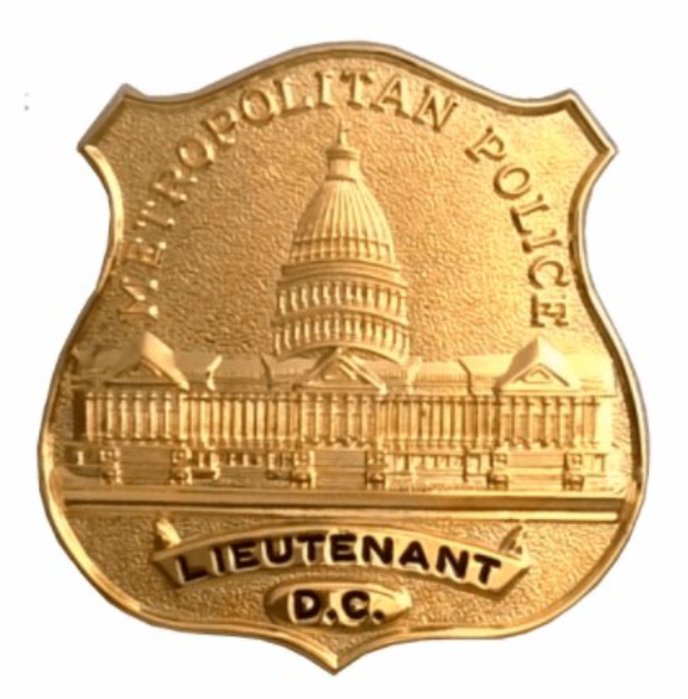 Goldenes Polizeimarke mit "Leutnant DC" eingraviert, mittig auf einem weißen Hintergrund.