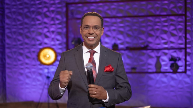 Plakat einer Person mit wildem Haar, weit aufgerissenen Augen und einem breiten Grinsen, vor einem hellgelben Hintergrund mit der Aufschrift "McFadden's Row of Flats: Die Comedy, die Millionen zum Lachen gebracht hat."