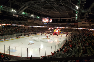 Ein Eishockeyspiel im Columbus Blue Jackets Stadion mit Zuschauern auf Sitzplätzen und Stehplätzen, einem eingezäunten Eis, Bannern und Überwachungsbildschirmen.