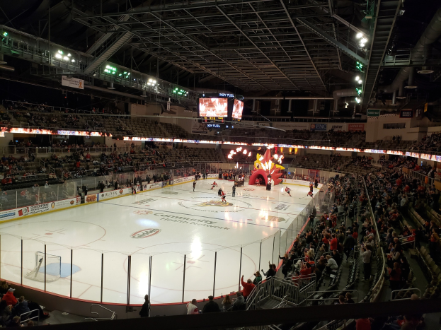 Ein Eishockeyspiel im Columbus Blue Jackets Stadion mit Zuschauern auf Sitzplätzen und Stehplätzen, einem eingezäunten Eis, Bannern und Überwachungsbildschirmen.