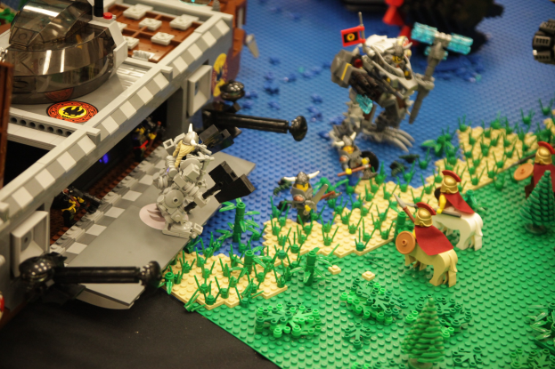 Lego-Schloss-Modell mit verstreuten Lego-Teilen, einschließlich Spielzeugen, Pflanzen und anderen Gegenständen.