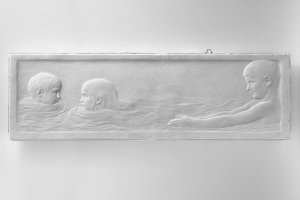 Drei Kinder schwimmen in einem Gewässer mit einer Wand im Hintergrund.