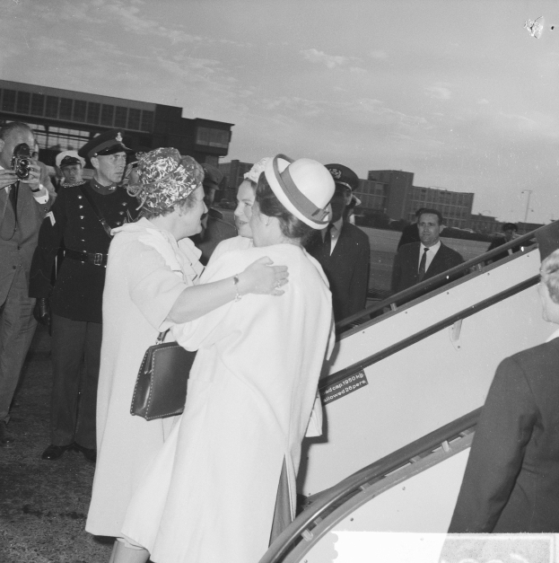 Königin Elizabeth II. und Prinz Philip, Herzog von Edinburgh, beim Ankunft am Heathrow Airport in London, mit zwei Frauen, die sich umarmen und ein Mann mit einer Kamera im Hintergrund.