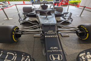 Ein McLaren Mercedes MP4-23 Formel-1-Auto bei der Singapore Grand Prix, umgeben von Barrieren, Verkehrskegeln, Menschen, Fahrzeugen, Pflanzen, Bäumen und einem Gebäude im Hintergrund.
