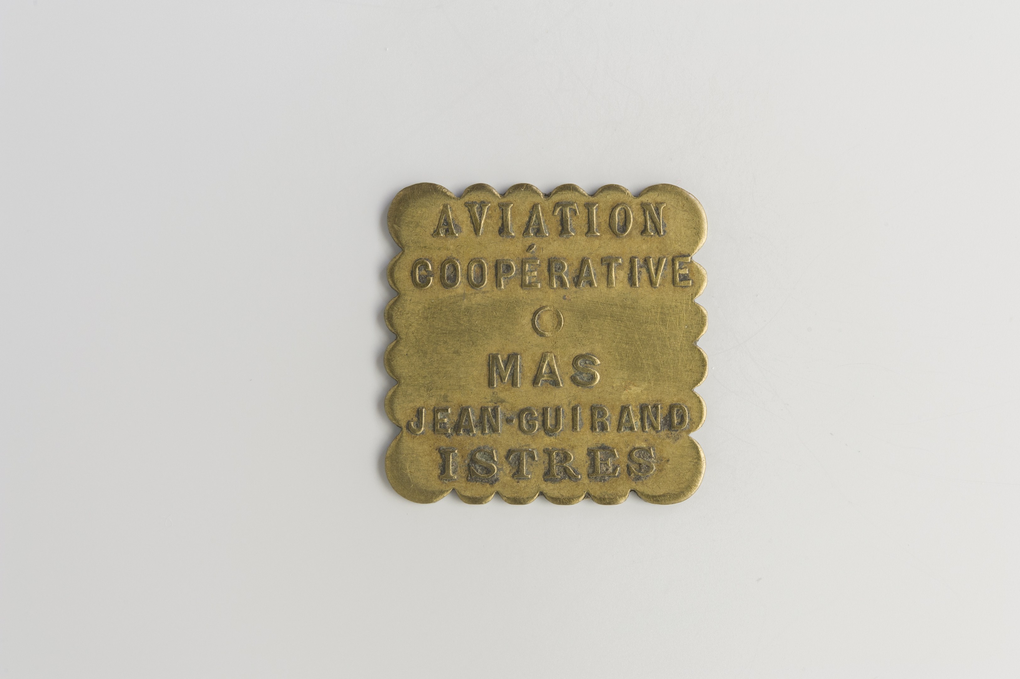 Messingtafel mit 'Luftfahrtgenossenschaft' eingraviert vor einem weißen Hintergrund.