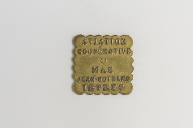 Messingtafel mit 'Luftfahrtgenossenschaft' eingraviert vor einem weißen Hintergrund.