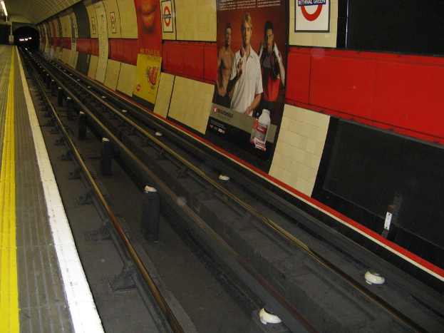 Eisenbahnschiene mit Plakaten an der Wand.