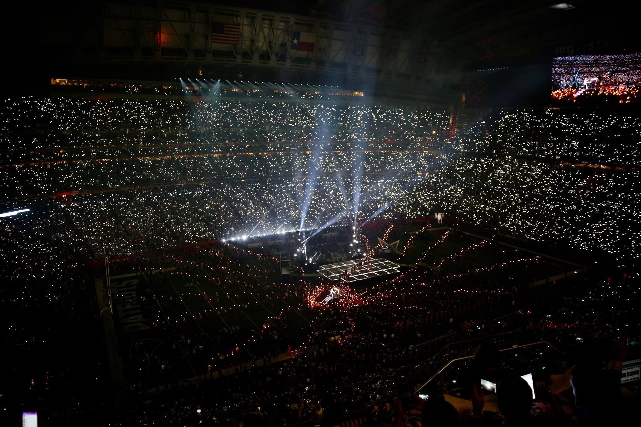Große Menschenmenge in einem hell erleuchteten Stadion bei Nacht, mit einem Bildschirm auf der rechten Seite, der die Ergebnisse der Super Bowl XLVII-Halbzeitshow anzeigt.