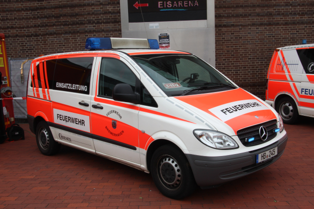 Zwei weiße Rettungswagen nebeneinander vor einem Gebäude geparkt, mit einem Feuerlöscher auf der linken Seite zu sehen.