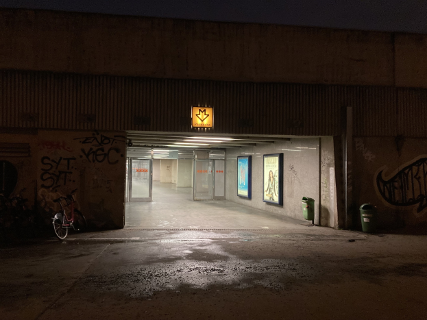 Leerer Parkplatz in der Nacht mit Graffiti-bedeckten Wänden, einem Fahrrad davor, einem nahen Müllcontainer, Rahmenwanddekorationen und sichtbarem Himmel im Hintergrund.