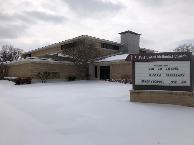 St. Paul United Methodist Church, ein Gebäude mit Fenstern und Türen, umgeben von Pflanzen und Bäumen, mit Schnee auf dem Boden und einem bewölkten Himmel im Hintergrund; ein Schild mit Text ist auf der rechten Seite sichtbar.