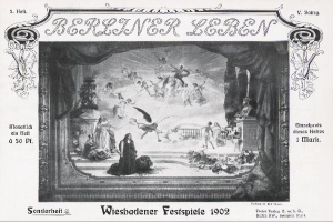 Ein Schwarz-Weiß-Foto einer Bühne bei den Wiesbadener Festspielen 1902, das Menschen in traditioneller deutscher Kleidung, farbige Lichter und Dekorationen sowie ein jubelndes Publikum zeigt.