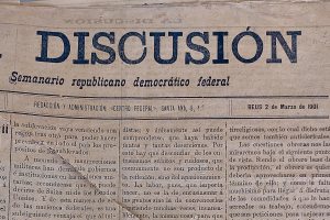 Ein gelblicher, leicht zerknitterter Zeitungsausschnitt mit schwarzer Tinte, der die Überschrift "Semanario Repúblicano Democrático Federal" und das Wort "Diskussion" auf der Seite zeigt.