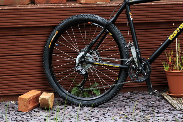 Ziegel, Steine, Pflanzen, eine Wand und ein Fahrrad im Freien.