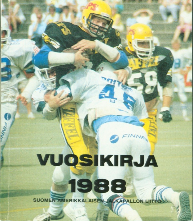 Gruppe von Menschen in Sportkleidung und Helmen, die Fußball auf einem Feld spielen, mit Zuschauern auf einer Treppe im Hintergrund; Text unten lautet "Vuosikirja 1988 - Suomen Amerikkaisen Jalkapallon Litto".