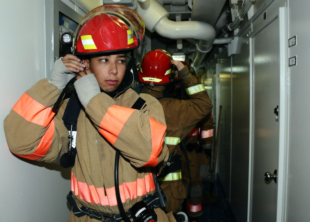 Feuerwehrleute in Uniform in einem Raum mit Rohren und Geräten während einer Übung.