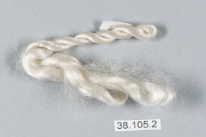 Ein Faden aus weißer Seide mit einer Zahl darauf, der auf einer grauen Oberfläche liegt.