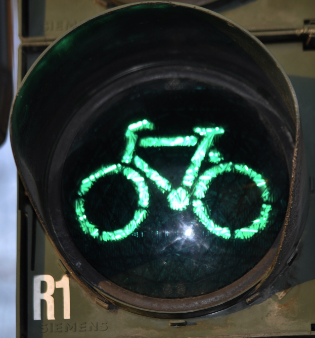 Grünes Ampelsignal mit Fahrradsymbol, das an einer Wand leuchtet.