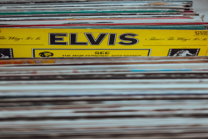 Ein Stapel Elvis-Presley-Platten ordentlich auf einem Tisch gestapelt, mit einigen Platten, die sich überschneiden und Titel sichtbar sind, vor einem leicht unscharfen Hintergrund.