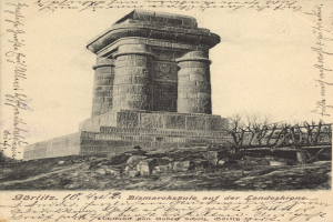 Alte Postkarte mit einer Zeichnung der Bismarcksäule auf der Landeskrone, umgeben von Bäumen und Felsen, mit der Beschriftung "Bismarcksäule auf der Landeskrone" unten.