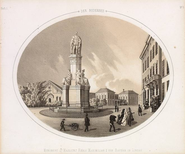 Schwarze und weiße Zeichnung einer Statue des Heiligen Majestrat König Maximilian I. von Bayern in einem Stadtplatz, umgeben von Gebäuden, Bäumen und Menschen, mit Text unten und dem Himmel im Hintergrund.