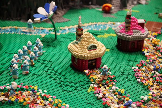 Ein Lego-Modell einer Kleinstadt mit bunten Blumen, Häusern, Pflanzen und Spielzeugen vor einem sanft unscharfen Hintergrund.