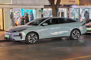 Ein Mitsubishi Lancer EV-Elektroauto nachts auf einer Straße geparkt, umgeben von Gebäuden, Geschäften, Schaufensterpuppen, Schildern und Lichtern.