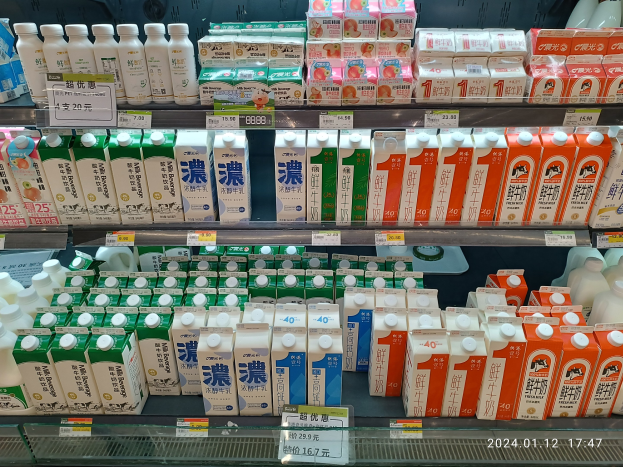 Eine Auslage in Japan mit verschiedenen Milcharten in Flaschen, Schachteln und anderen Behältern, jeweils mit Preisschildern.