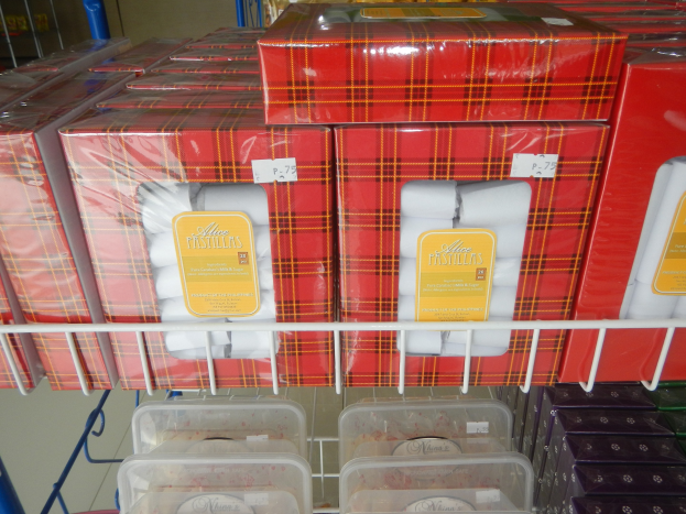 Ein Ladenelement, das mit verschiedenen Toilettenpapierprodukten in Kartons und Plastikverpackungen gefüllt ist, mit zusätzlichen Artikeln auf den Regalen und einer Wand im Hintergrund.