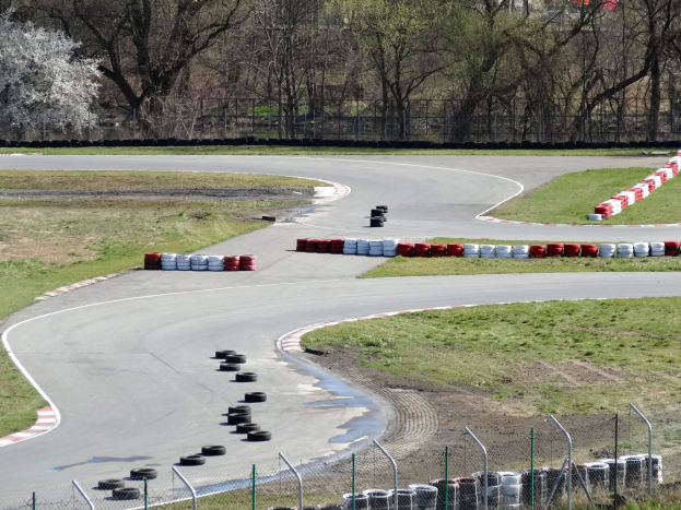Rennstrecke mit zahlreichen Reifen darauf, von Gras und Maschendrahtzaun umgeben, mit Bäumen im Hintergrund.