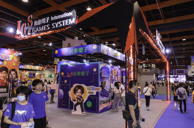 Eine Gruppe von Menschen, die durch den Convention Hall einer Gaming-Messe in China gehen, einige mit Taschen und Gegenständen in der Hand, mit Display-Boards, Deckenbeleuchtung und Teppichboden.