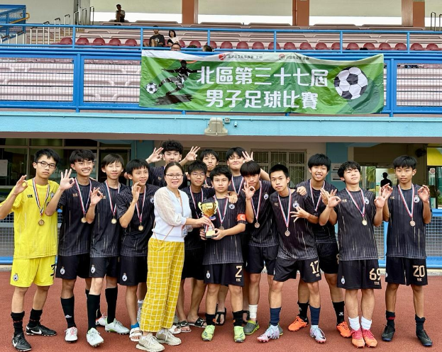 Gruppe junger Männer in Fußballtrikots auf einem Feld mit einem Pokal, Medaillen tragend, mit einem Banner "Yokohama U-16 Jungenfußballmannschaft" im Hintergrund.