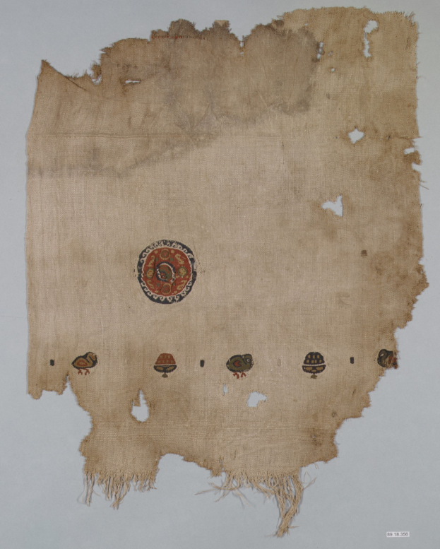 Ein Stoffstück mit einem kreisförmigen Design, das leuchtende Farben und detaillierte Formen wie Kreise, Quadrate und Dreiecke auf einem weißen Hintergrund zeigt.