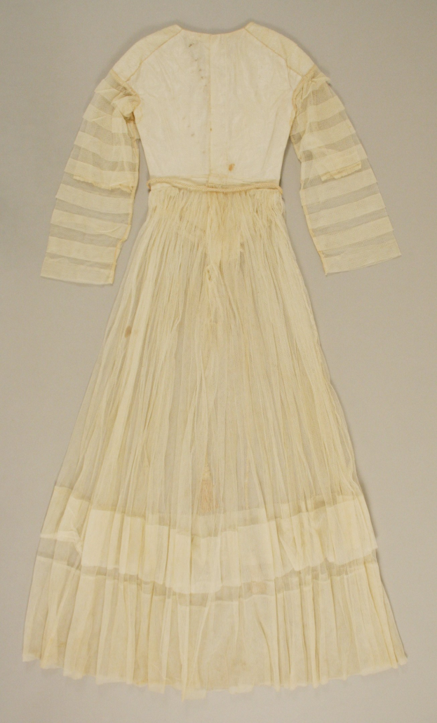 Ein weißes, langärmeliges Kleid mit einer gerafften, bodenlangen Schleppe auf einer weißen Oberfläche, das einen hohen Taillenbund und einen dezenten Schimmer aufweist.