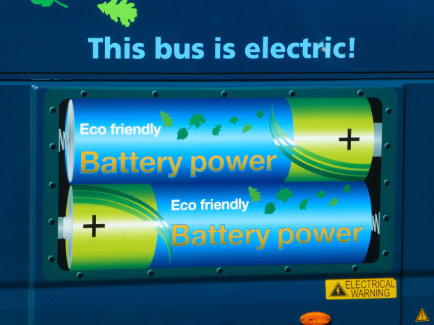 Blauer Elektrobus mit "Dieser Bus ist elektrisch"-Schriftzug und zwei sichtbaren Seitenspeichern.