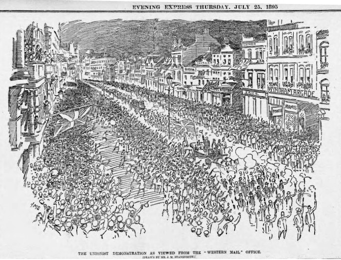 Schwarze und weiße Zeichnung einer Menge, die eine von Gebäuden gesäumte Straße entlanggeht, mit dem Text "Die Unionistendemonstration, wie sie vom Western Mail Office aus betrachtet wird" oben und unten.