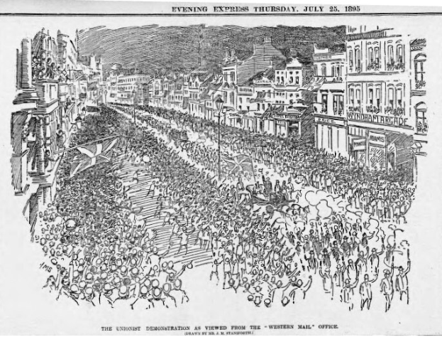 Schwarze und weiße Zeichnung einer Menge, die eine von Gebäuden gesäumte Straße entlanggeht, mit dem Text "Die Unionistendemonstration, wie sie vom Western Mail Office aus betrachtet wird" oben und unten.