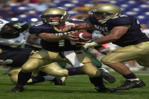 Ein Fußballspieler in einem Sportdress und Helm rennt mit dem Ball, umgeben von anderen Spielern in ähnlicher Kleidung, mit einem unscharfen Hintergrund.